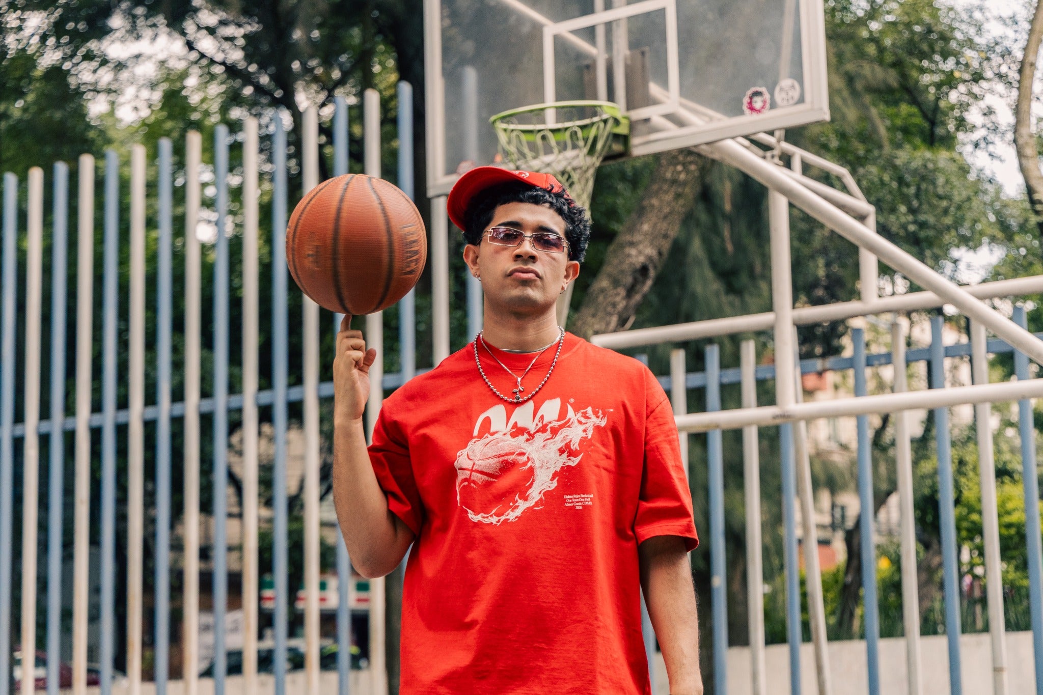 Modelo con Fireball Tee roja y balón en cancha exterior.